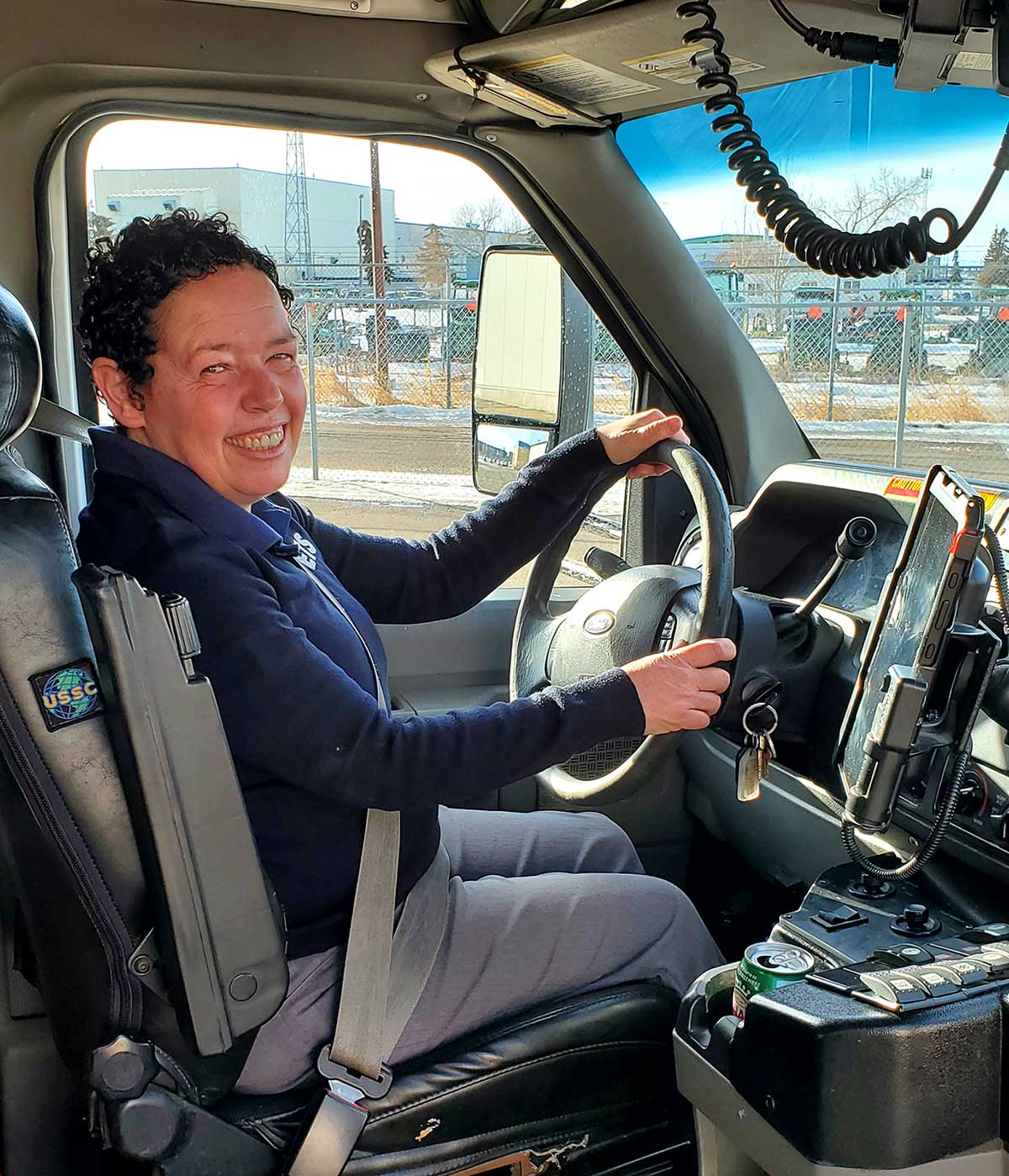 Michelle gleefully in the drivers seat of a DATS vehicle