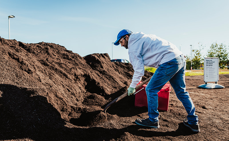 Someone shoveling compost at an ecostation