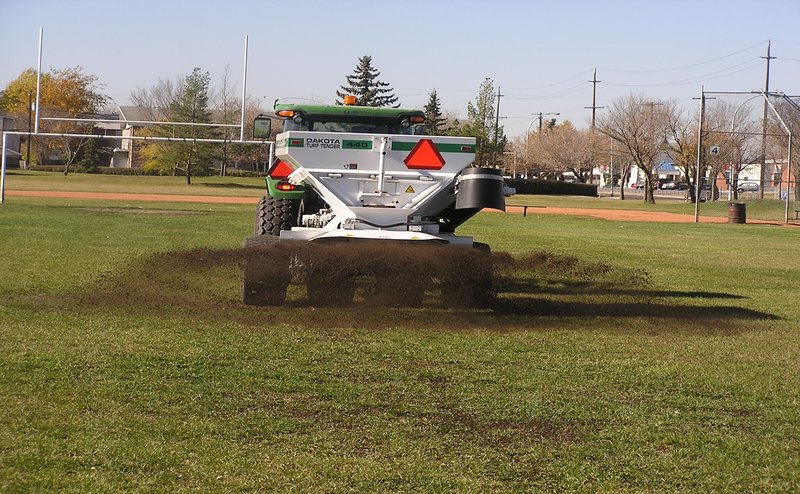 Dakota topdresser, turf equipment spreading topsoil in a sports field