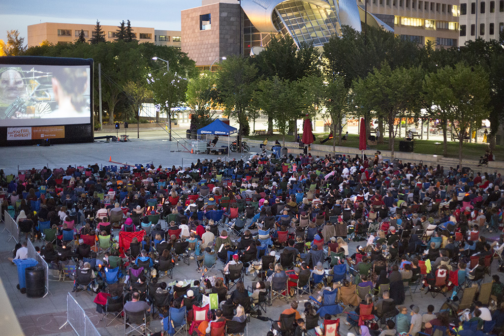 crowd of people watching a movie on the big screen