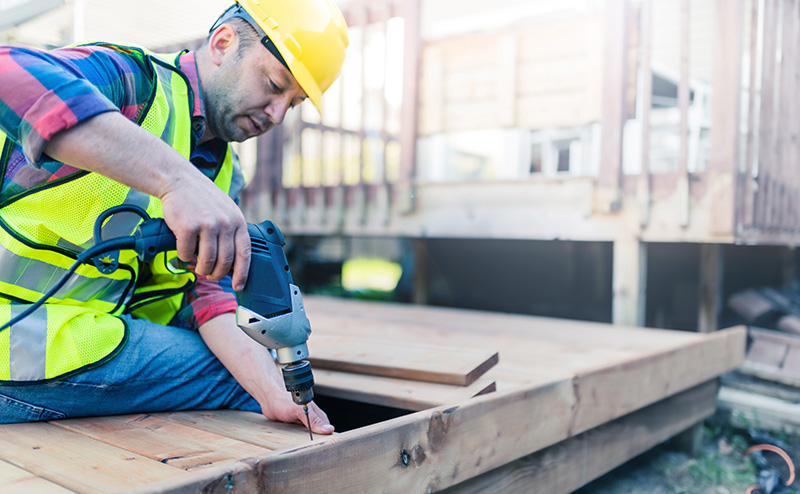 Carpenter with drill installing wood deck