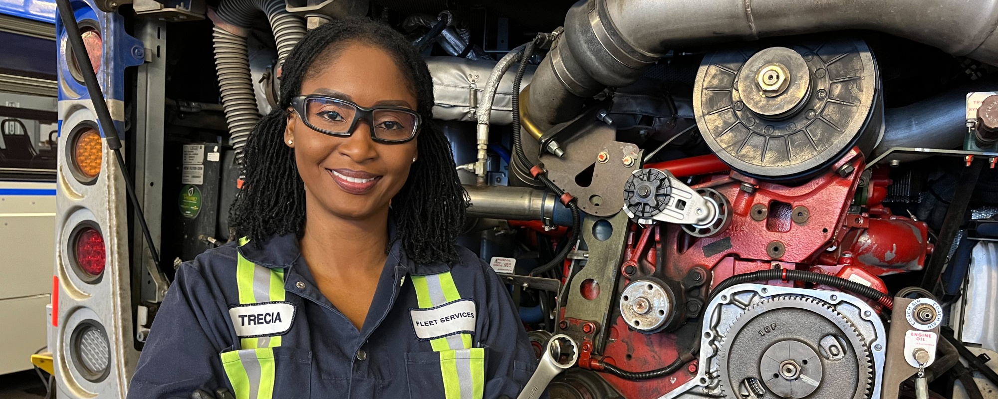 Heavy equipment technician standing in front of bus motor