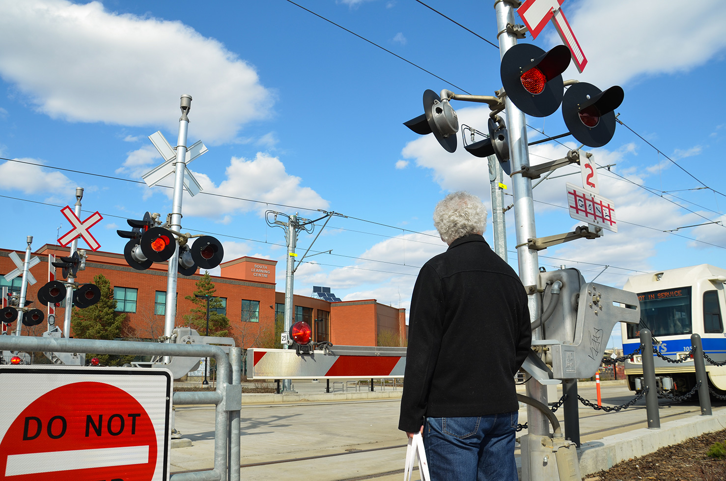 Man standing behind a train crossing gate