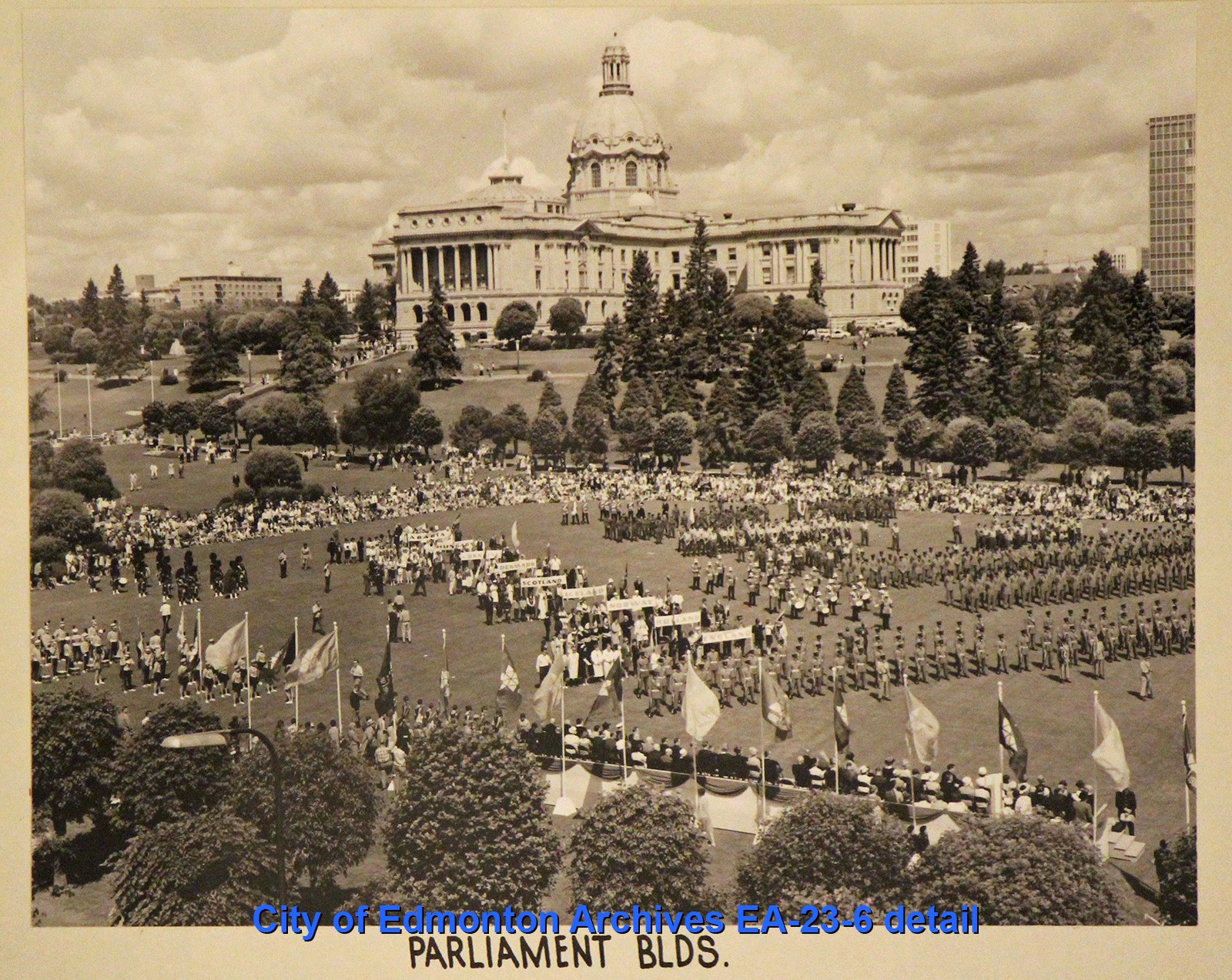 A black and white photograph of a celebration taking place in front of the Alberta Legislature Building.