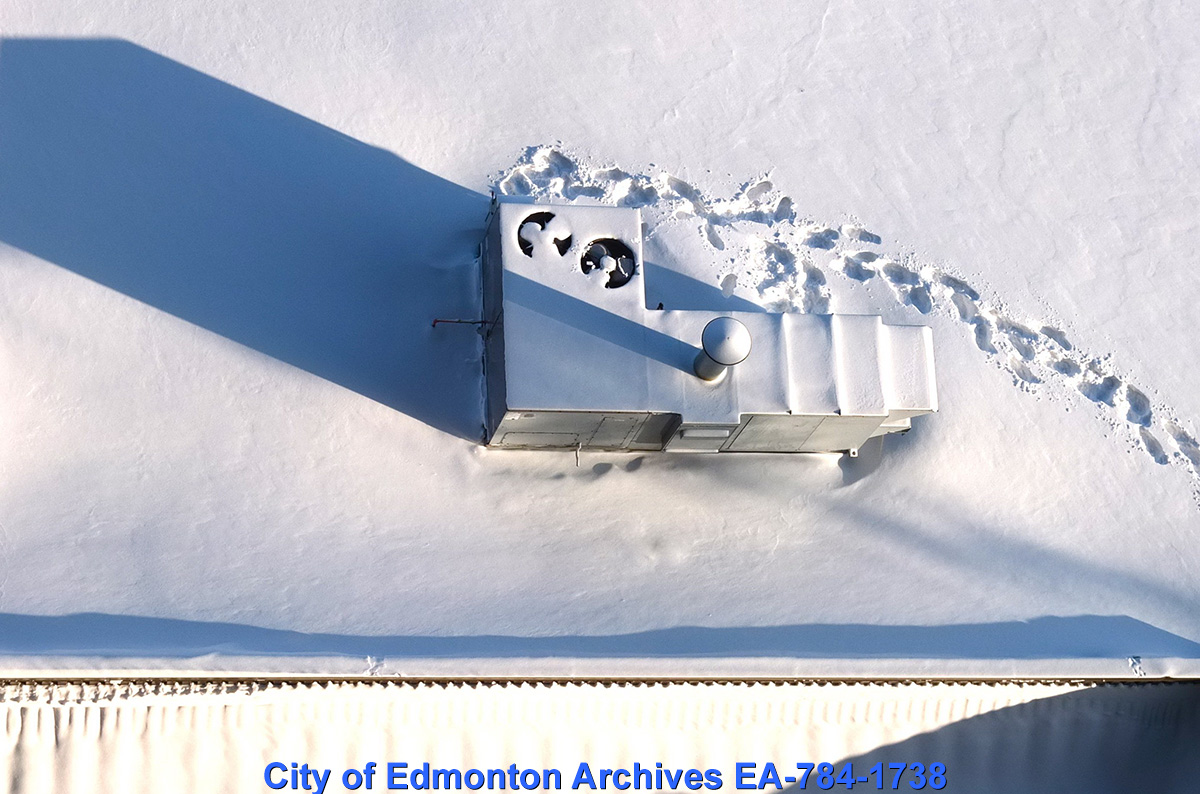 An overhead view of a metal structure in the snow, and footprints in the snow leading away from it.