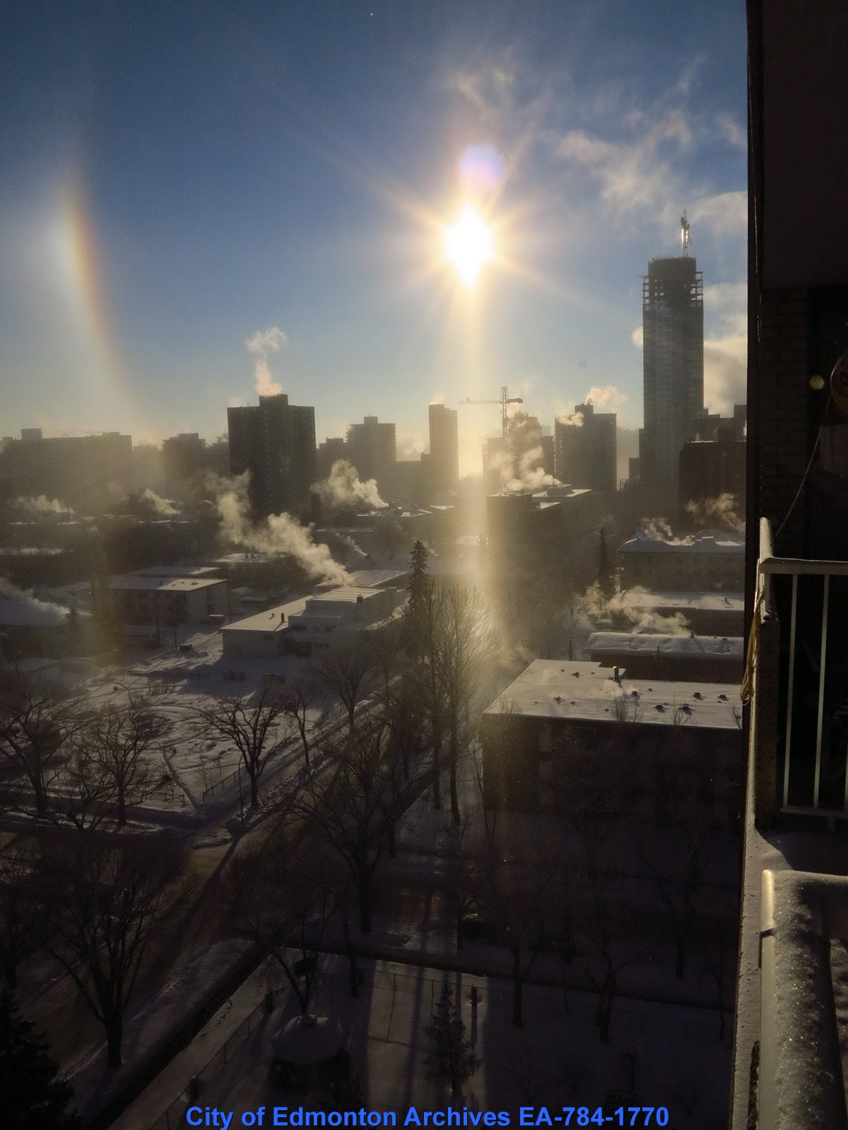 An overhead view of Edmonton building in winter, with the sun shining as a focal point.