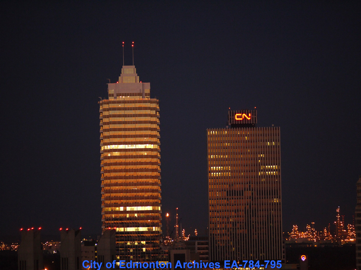 Two downtown Edmonton towers with their lights on at night.