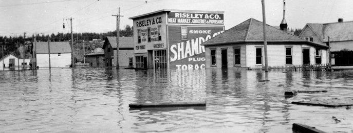 Buildings that are half submersed in water, and debris floating on top of the water.