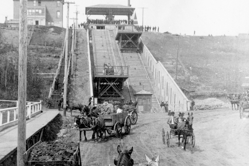 Horse-drawn carriages near an inclining wooden railway.
