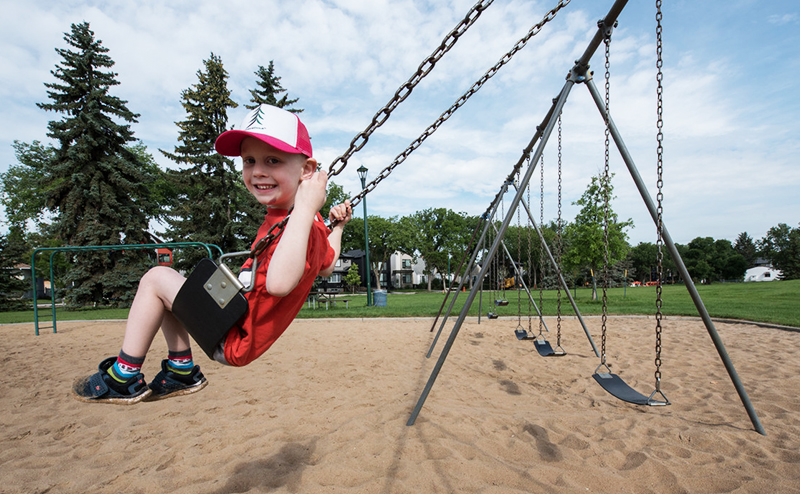 A boy in a hat on a swing.