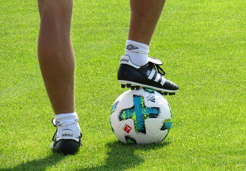 A soccer player resting his foot on a soccer ball