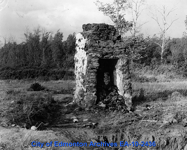The ruins of a stone chimney standing alone in a field