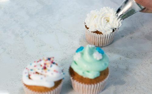 person icing cupcake