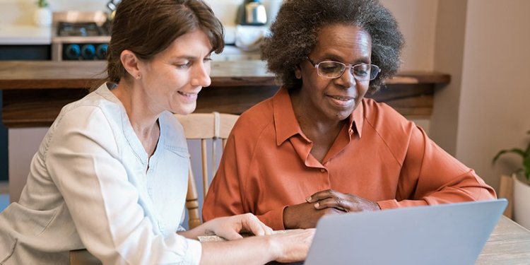 female helping senior at laptop