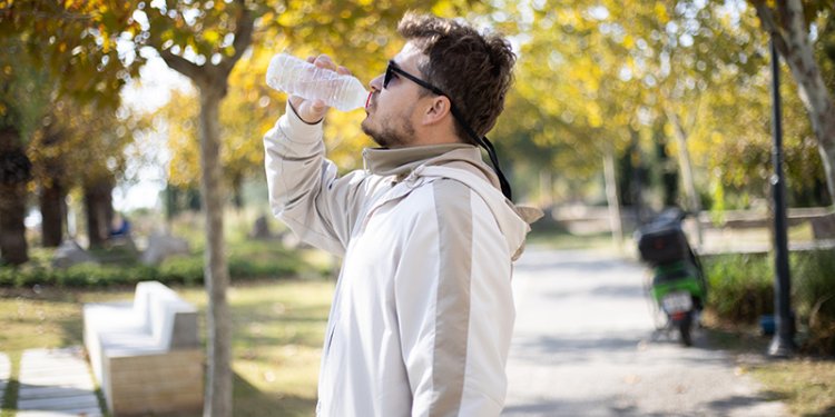 man drinking water from bottle in park