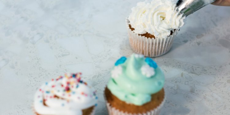 person icing cupcake