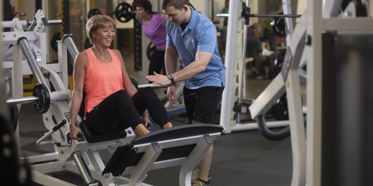 Personal trainer working with woman on leg press
