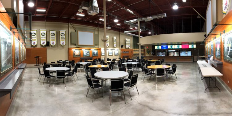 A large room with multiple round tables and chairs.
