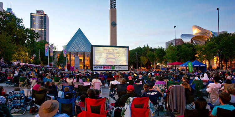 persons sitting in Churchill Square watching movie on big screen
