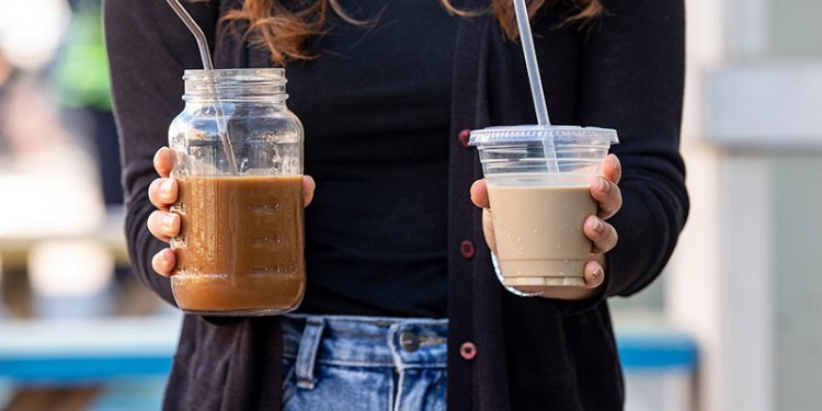 person holding a plastic and a glass cup