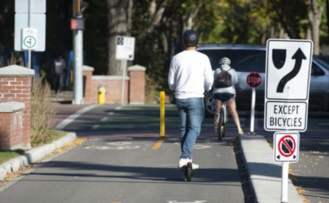 person riding e-scooter down bike lane