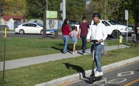 person riding e-scooter with helmet on