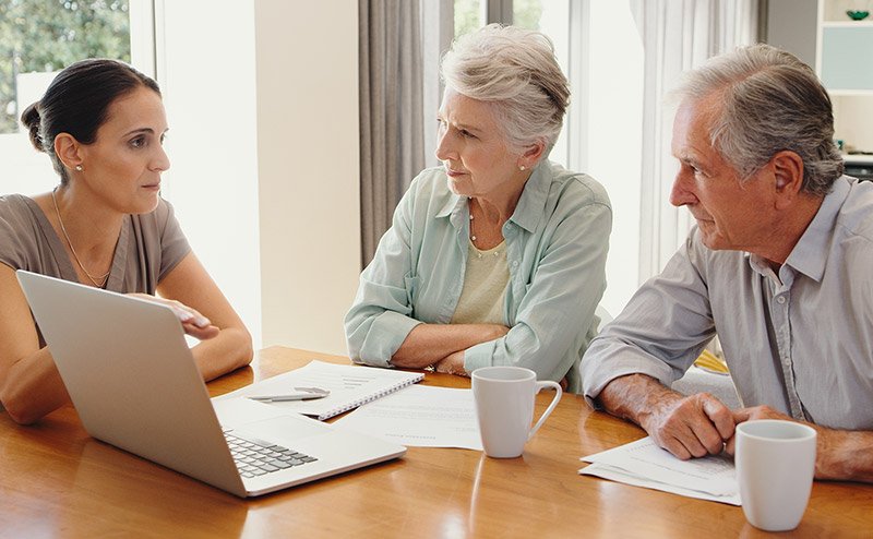 seniors sitting with laptop speaking to younger female