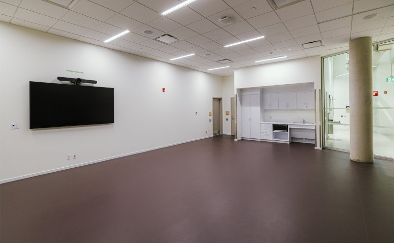 Multi-purpose room with sink, cupboards and a wall-mounted TV.