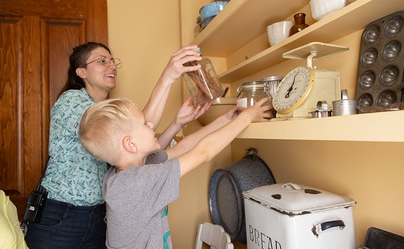 Woman and child reaching for some containers on a shelf
