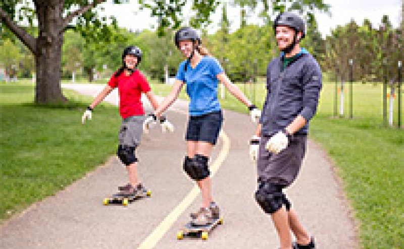 Three people skateboarding down a trail.