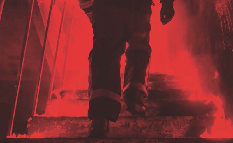 Firefighter running up burning stairs