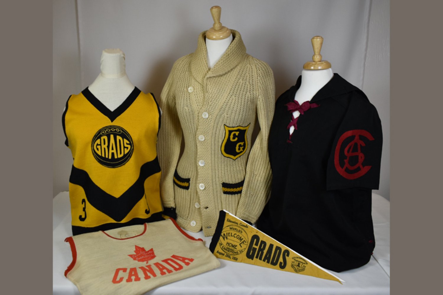 Various Grads uniforms and a flag on display.