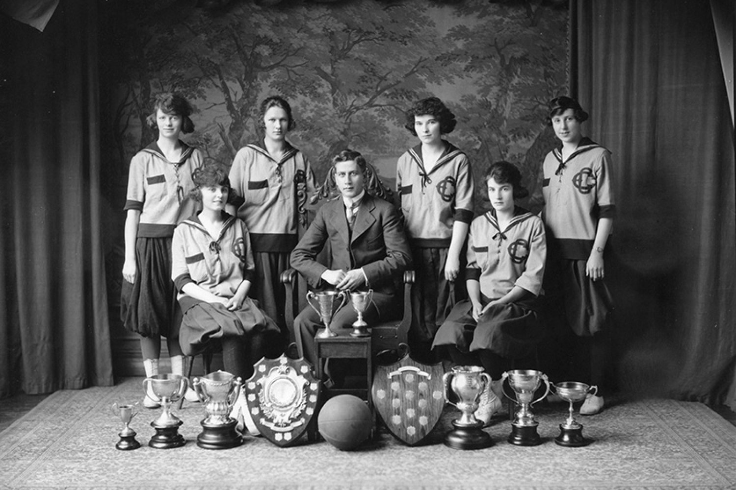 Black and white photo of the Edmonton Grads, Coach Percy Page, and several awards.