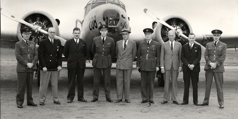 No 2 AOS and Canadian Airways staff posing in front of the nose of an airplane