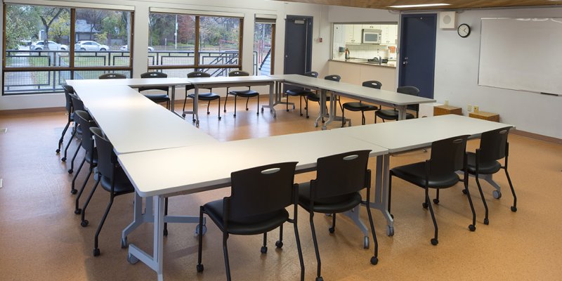 room with square table and chairs with adjoining kitchen