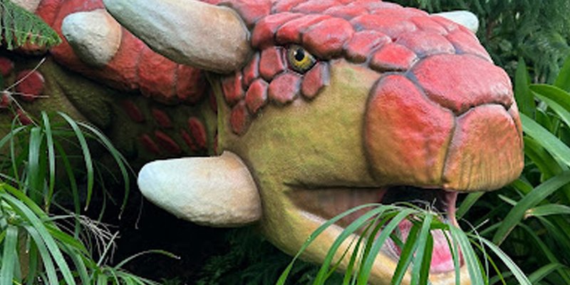 Sculpture of a dinosaur placed to look like it's eating real plants.