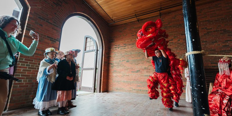 People watching a Chinese lion dance demonstration at Fort Edmonton Park.