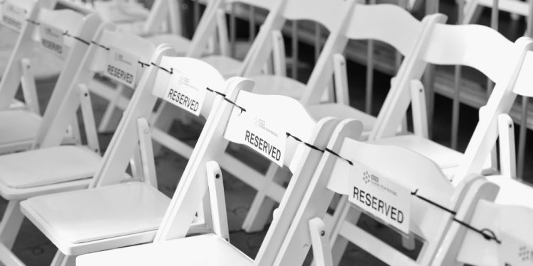 white chairs set up in rows with reserved signs