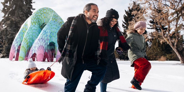 family sledding in park at winter