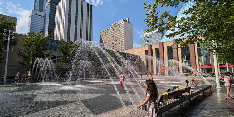 Water spraying from a fountain at City Hall, kids are seen playing near it.