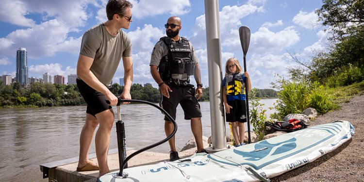 three persons by boat launch dock with paddleboard and paddle
