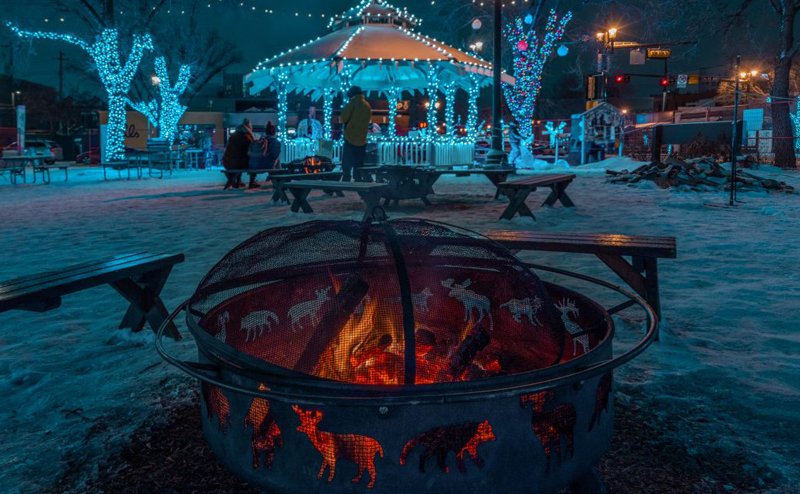 A firepit in front of a gazebo in winter at night.
